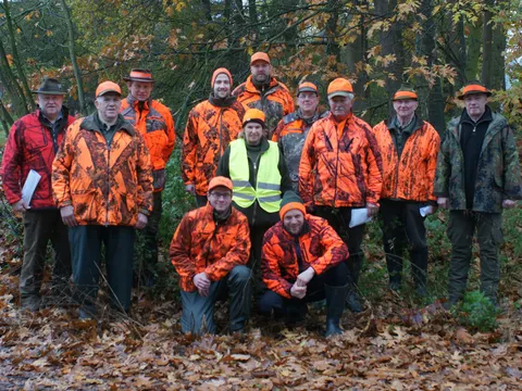 Gruppenbild der Jägerschaft Varl: Jägerinnen und Jäger in orangefarbener Signalkleidung am Waldrand im Herbstlaub