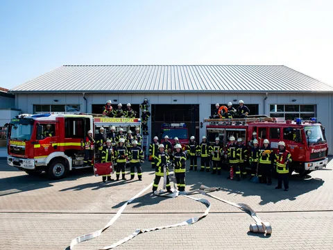 Die Einsatzkräfte der Freiwilligen Feuerwehr vor dem Gerätehaus, flankiert von zwei roten Löschfahrzeugen